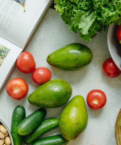 An appetizing display of fresh fruits and vegetables with a cookbook, perfect for healthy recipes.