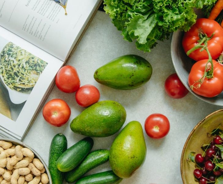 An appetizing display of fresh fruits and vegetables with a cookbook, perfect for healthy recipes.