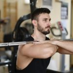 A focused man lifting weights indoors showcasing strength and concentration.