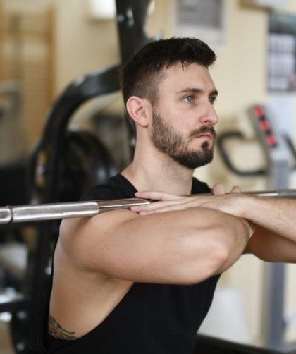 A focused man lifting weights indoors showcasing strength and concentration.