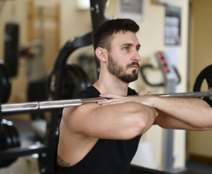 A focused man lifting weights indoors showcasing strength and concentration.